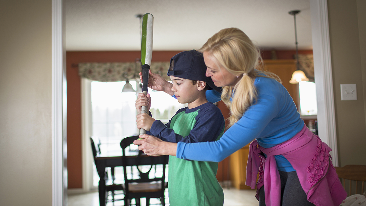 Mother teaching child to play baseball