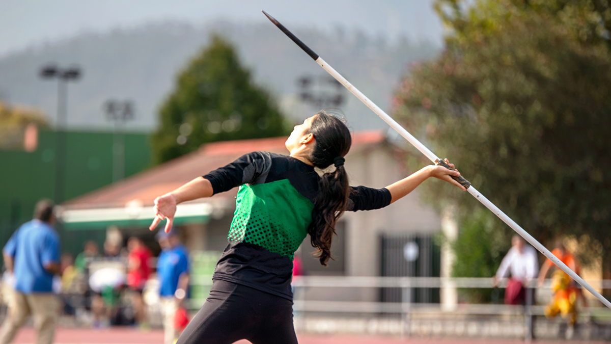 Girl with ponytail winds up to throw javelin on track