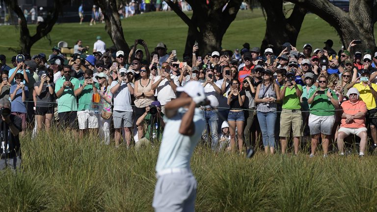 Fans take pictures as Tiger Woods hits his tee shot at hole No. 18 during the third round of the Arnold Palmer Invitational