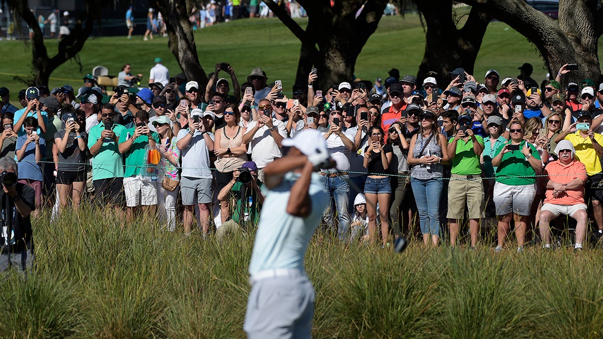 Fans take pictures as Tiger Woods hits his tee shot at hole No. 18 during the third round of the Arnold Palmer Invitational