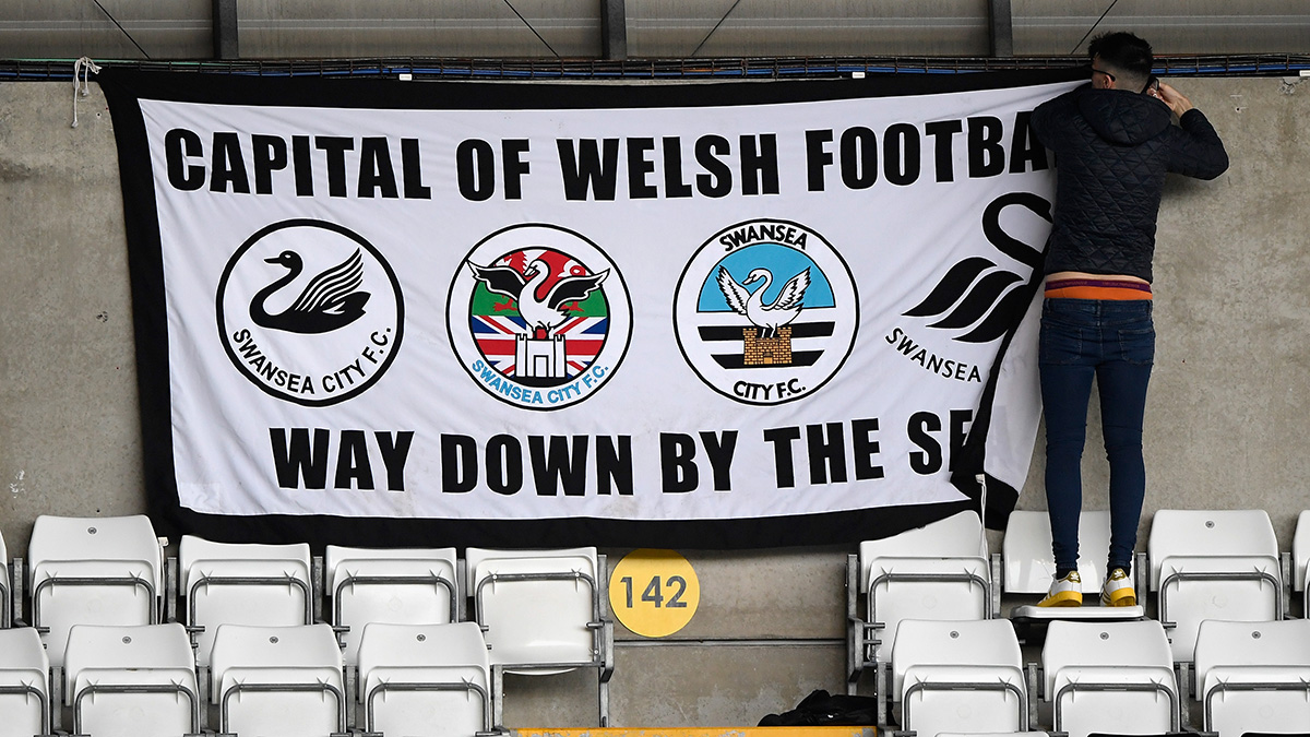 A supporter of Swansea City Football Club hangs up a flag before a match