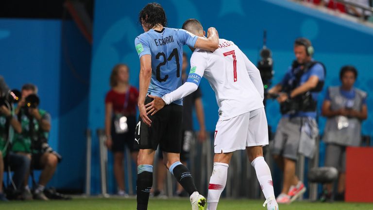 Christiano Ronaldo drapes injured Edison Cavani's arm over him to help Cavani off the field during World Cup soccer game