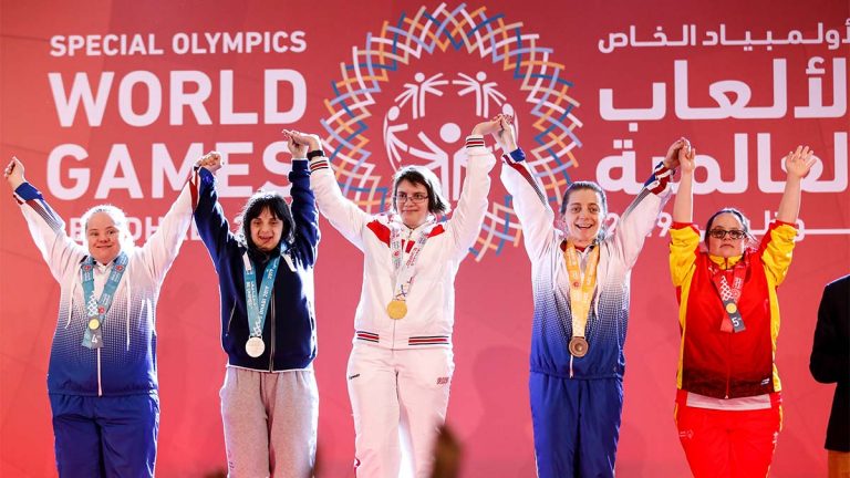 Five woman celebrating on the podium with their medals
