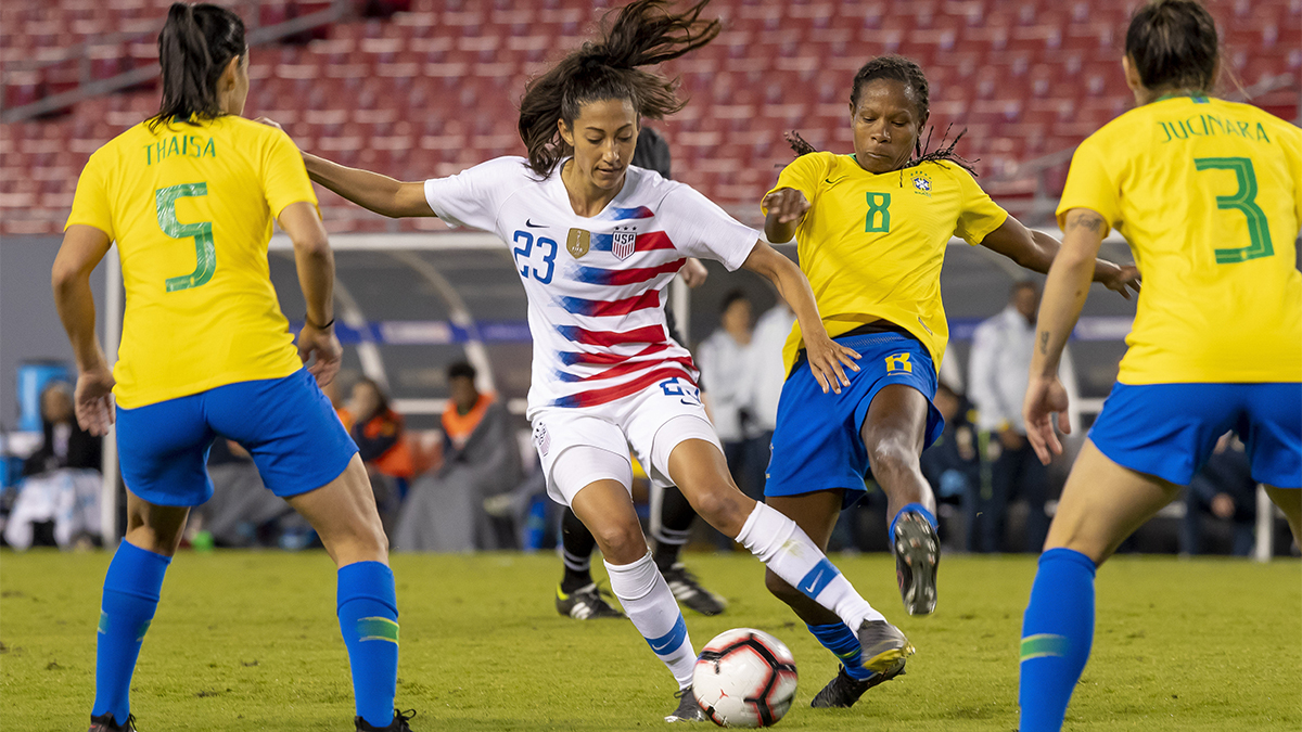 Christen Press of the U.S. dribbles ball through Brazil players in the She Believes Cup in 2019