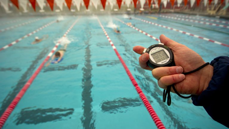 Swimmers, coach with timer