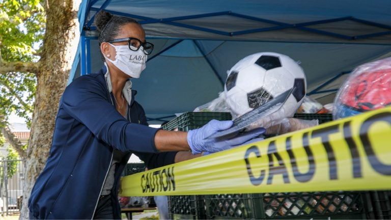 LOS ANGELES, CA - MAY 06: Renata Simril, of LA84, Foundation, distributes sports goods to under-served kids, at LAUSD Grab and Go meal center at Thomas Alva Edison School. Thomas Alva Edison Middle School on Wednesday, May 6, 2020 in Los Angeles, CA. (Irfan Khan / Los Angeles Times via Getty Images)