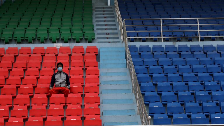 One person wearing a protective mask in an empty stadium at a sports event.