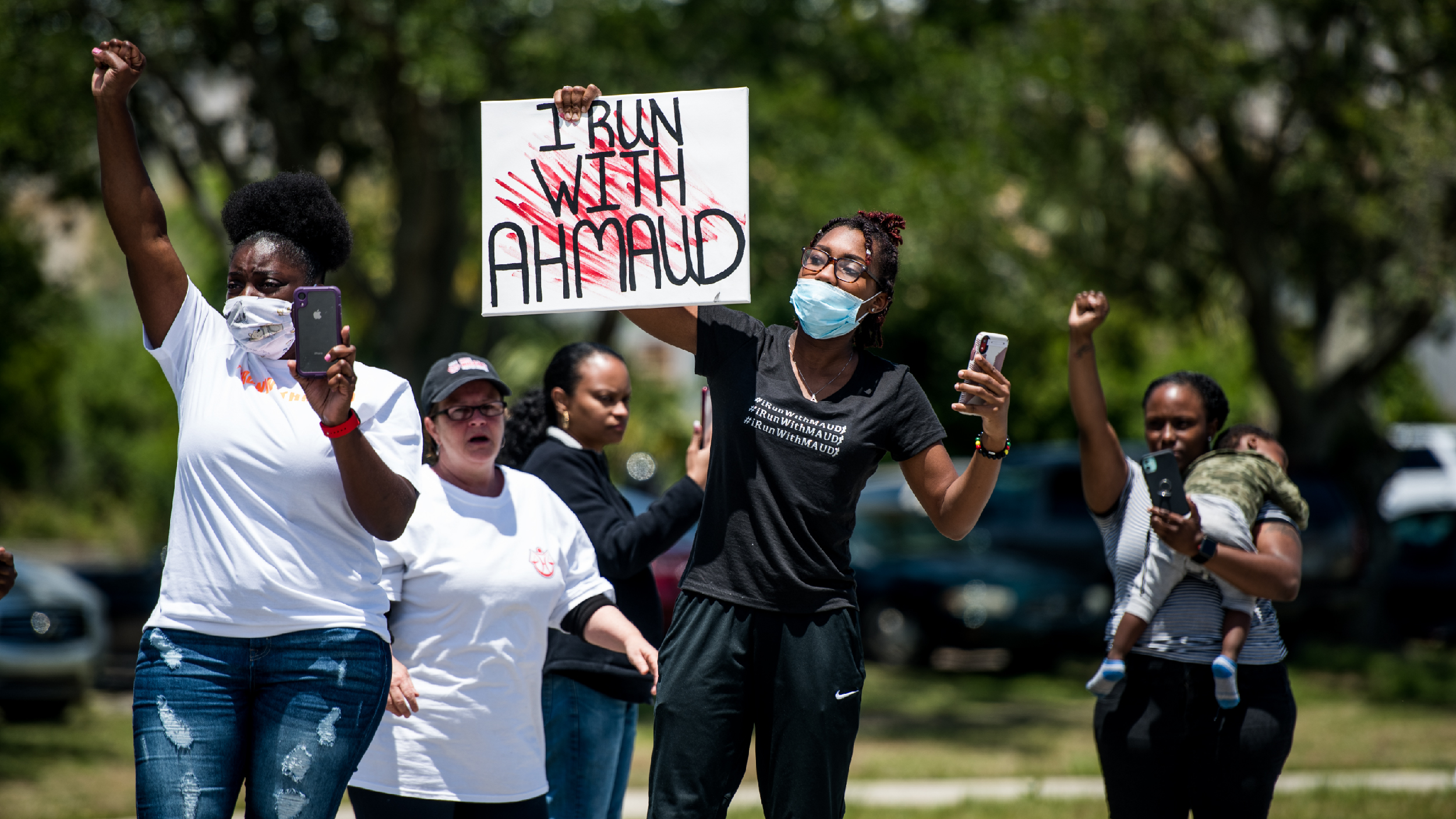BRUNSWICK, GA - MAY 09: Demonstrators raise their fists at a parade of passing motorcyclists riding in honor of Ahmaud Arbery at Sidney Lanier Park on May 9, 2020 in Brunswick, Georgia. Arbery was shot and killed while jogging in the nearby Satilla Shores neighborhood on February 23. (Photo by Sean Rayford/Getty Images)