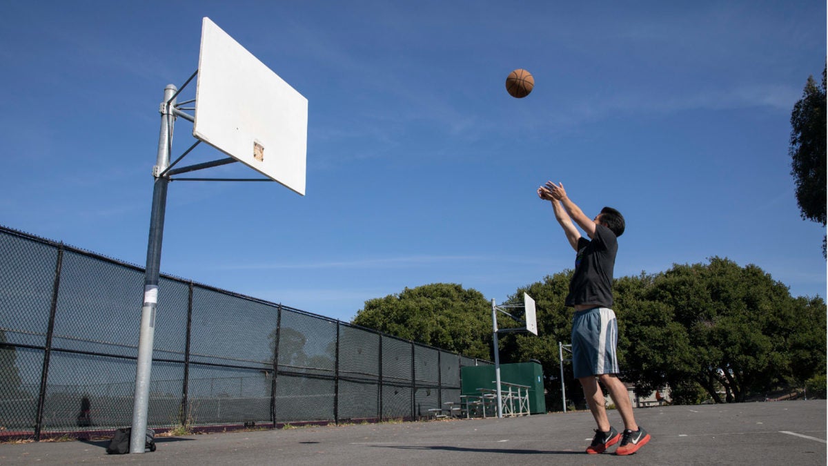 SAN FRANCISCO, CALIFORNIA - MAY 07: A man plays basketball after baskets are removed from basketball hoops at Mills High School on May 07, 2020 in San Francisco, California. The school removes baskets from basketball hoops to prevent people from gathering to play basketball. (Photo by Liu Guanguan/China News Service via Getty Images)