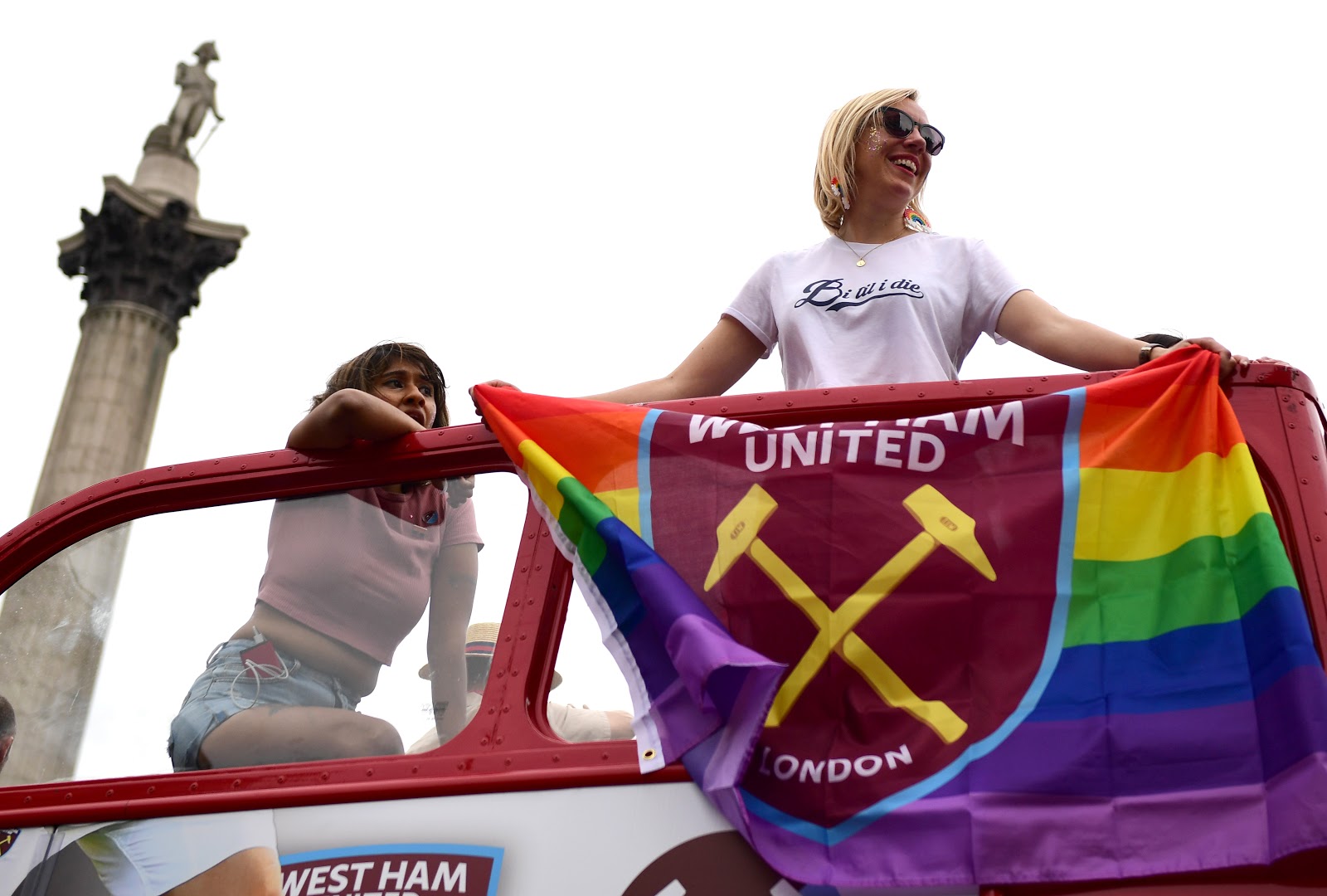Pride supporters holding a LGBT pride flag on a bus in London.