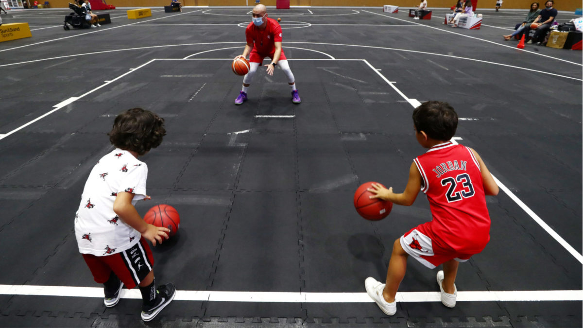 DUBAI, UNITED ARAB EMIRATES - JULY 08: A basketball coach show kids how to dribble a ball at Dubai Sports World on July 08, 2020 in Dubai, United Arab Emirates. Dubai Sports World is the UAE’s largest indoor summer sports venue. (Photo by Francois Nel/Getty Images)