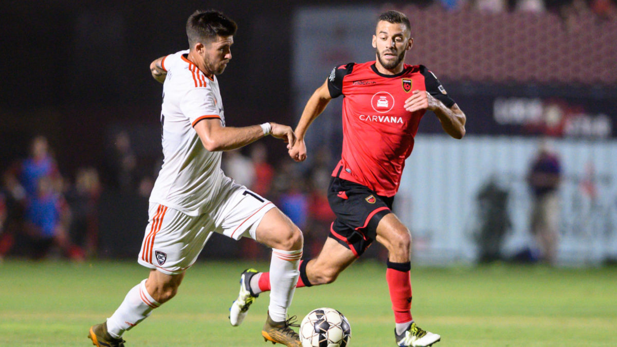 PHOENIX, ARIZONA - JUNE 15: Aodhan Quinn #14 of Orange County SC is challenged for the ball by Joey Calistri #21 of Phoenix Rising FC during the USL match between Orange County FC and Phoenix Rising FC at Casino Arizona Field on June 15, 2019 in Phoenix, Arizona. (Photo by Joe Hicks/Getty Images)