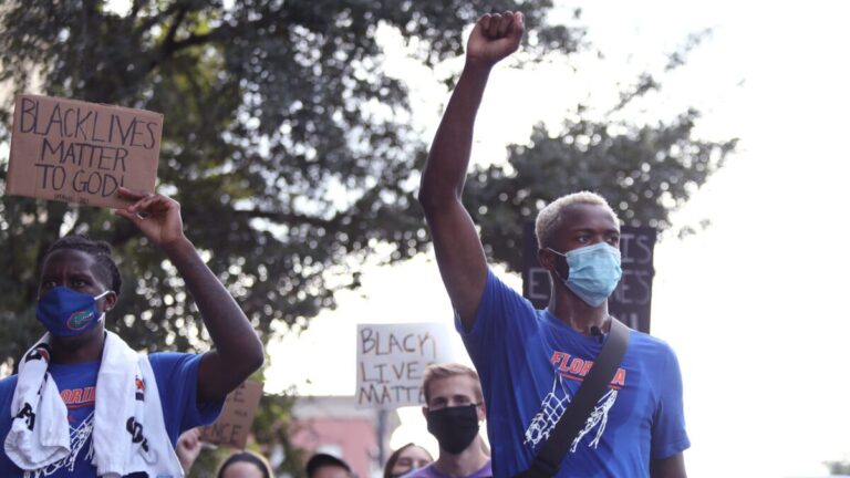 University of Florida athletes Scottie Lewis and Anthony Duruji march with Black Lives Matter signs.