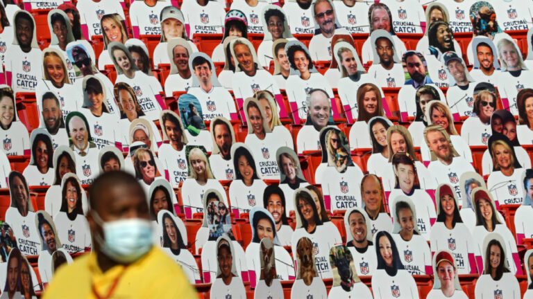 LANDOVER, MARYLAND - OCTOBER 04: Cardboard cutouts of fans are seen in the spectator seating in front of a security guard wearing a surgical face mask during the second half at FedExField on October 4, 2020 in Landover, Maryland. Due to the coronavirus pandemic, the Washington Football Team did not host fans during the game. (Photo by Patrick Smith/Getty Images)