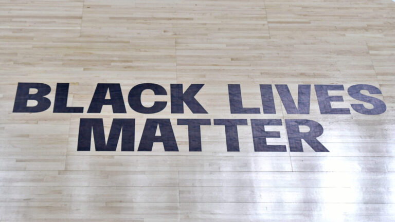 A Black Lives Matter logo on a basketball court floor
